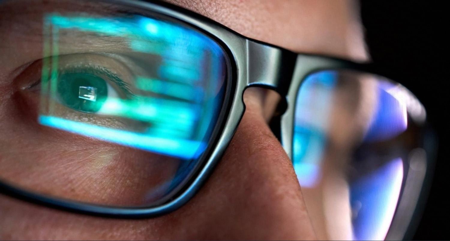 Close-up of an IT engineer's glasses reflecting monitoring dashboards